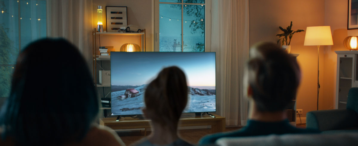 Family gathering in a living room, engaged in watching a large screen television