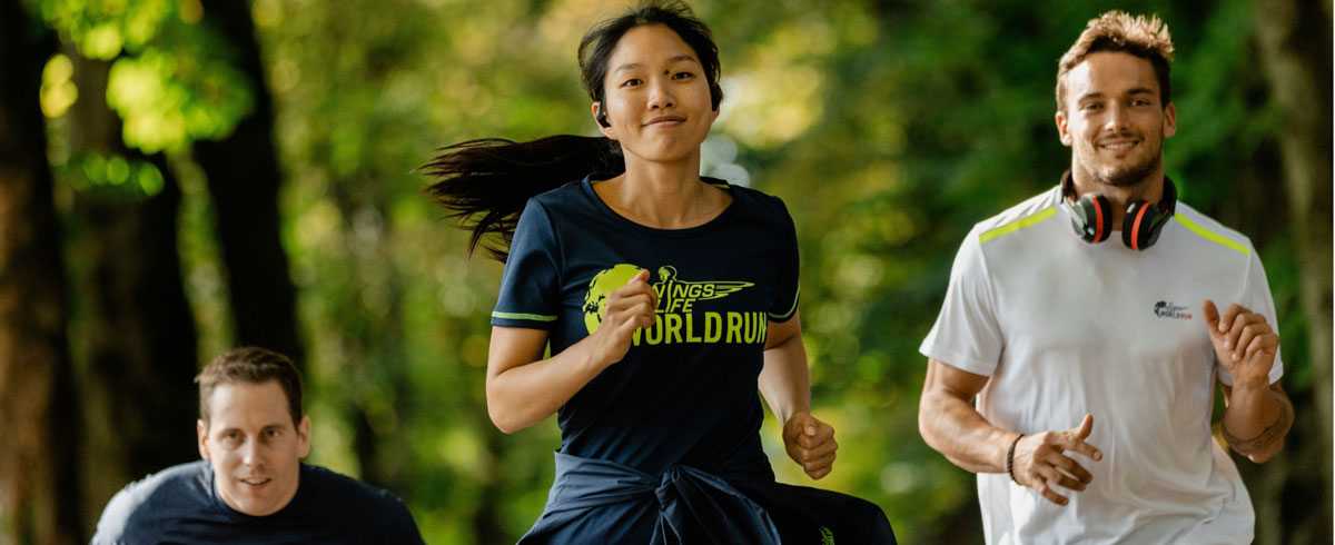 Three Wings for Life World Run participants are joyfully running, wearing Philips sports headphones.